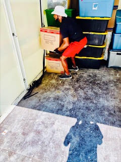 Worker in orange clothing bending down near shelving units in storage area