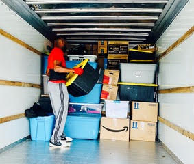 Woman organizing storage unit with boxes, tools, and household items